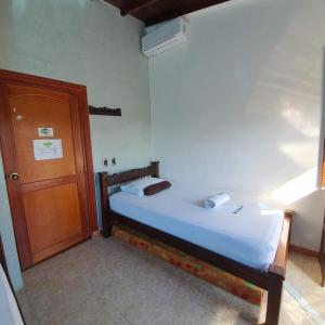 a small bed in a room with a wooden door at Hotel Las Golondrinas in Puerto Berrío