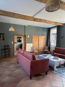 a living room with two couches and a table at Le Sart de Bouland in Frasnes-lez-Anvaing
