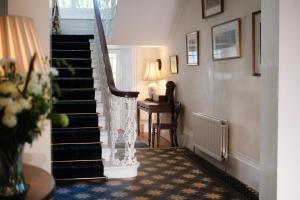 a hallway with stairs and a table and a lamp at Burnhopeside Hall in Lanchester
