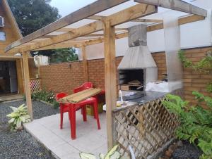 a wooden pergola with a table and a bench and a grill at Chalé solmar in Penha +3 photos