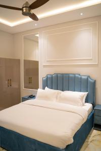 a bedroom with a large bed with a blue headboard at The Edition Signature in Bahawalpur