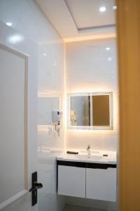 a white bathroom with a sink and a mirror at The Edition Signature in Bahawalpur