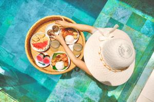 a woman in a hat sitting next to a plate of food at Palm Villa Prawirotaman in Timuran