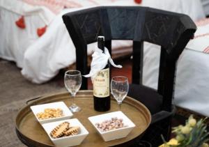 a table with a bottle of wine and wine glasses at Sahara Legacy Camp in Merzouga +20 photos