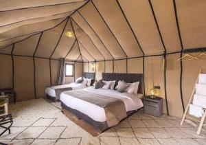 a bedroom with two beds in a tent at Sahara Legacy Camp in Merzouga