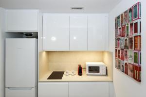 a kitchen with white cabinets and a microwave at Los Juncos HomeStay by Turismar in La Pineda