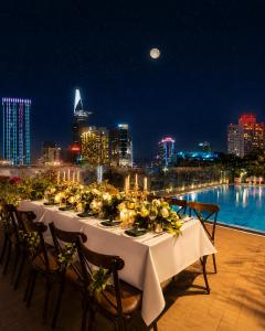 a long table with flowers and candles on a rooftop at Happy Life Grand Hotel & Rooftop Skybar in Ho Chi Minh City
