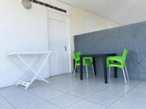 a room with a table and two green chairs at Bel appartement à Damencourt in Le Moule
