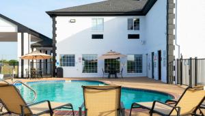 a pool with chairs and umbrellas in front of a house at Atria Hotel and RV McGregor in McGregor