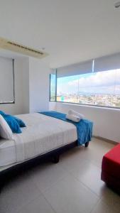 ein Schlafzimmer mit einem großen Bett und einem großen Fenster in der Unterkunft Lujoso Dpto vista a ciudad Edificio Poseidón in Manta + 35 Fotos