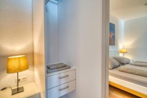 a bedroom with a bed and a lamp on a dresser at Ferienpark - Haus H, App 0H1107 - Apartment Baltic Panorama in Heiligenhafen