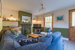 a living room with a blue couch and a fireplace at Pebble Beach Cottage by Keepers Cottages in Kingsdown