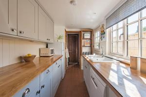 a kitchen with white cabinets and a wooden counter top at Pebble Beach Cottage by Keepers Cottages in Kingsdown +17 photos