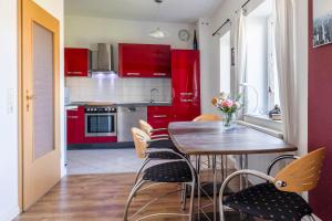 a kitchen with red cabinets and a wooden table and chairs at Ferienwohnung Schlossperle in Klütz