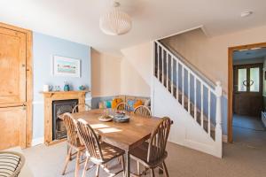 a dining room with a table and chairs and a staircase at Pebble Beach Cottage by Keepers Cottages in Kingsdown
