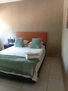 a bedroom with a large bed with green pillows at Traquil Stays BnB in Klerksdorp