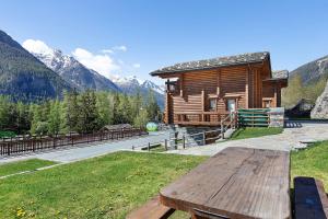 a wooden cabin in the mountains with a picnic table at Chez Duclos Bionaz in Bionaz