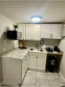 a kitchen with white cabinets and a sink and a microwave at Rosa Bella Comfort Suite in Homestead