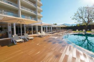 a pool with chairs and umbrellas next to a hotel at Prestige Goya Park in Roses
