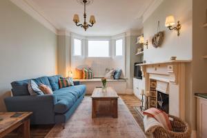 a living room with a blue couch and a fireplace at Whispering Waves by Keepers Cottages in Hythe