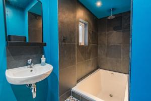 a bathroom with a sink and a bath tub at Whispering Waves by Keepers Cottages in Hythe