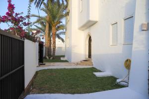 a white house with a gate and palm trees at Villa l'olivier in Djerba