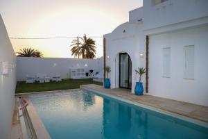 a house with a swimming pool in front of a house at Villa l'olivier in Djerba