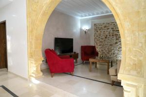 a living room with two red chairs and a tv at Villa l'olivier in Djerba