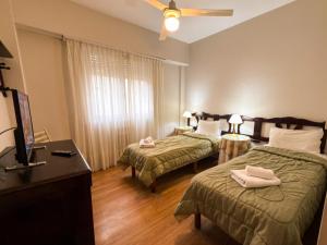a hotel room with two beds and a flat screen tv at Gran Hotel Mar del Plata in Mar del Plata