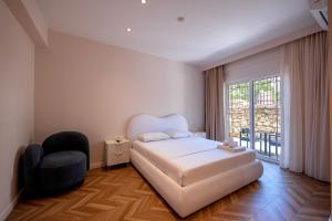 a bedroom with a bed and a chair and a window at Hotel Almar in Sarandë