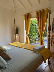 a bedroom with a bed with yellow curtains and a window at Calme avec vue formidable sur l'océan in Cul de Sac