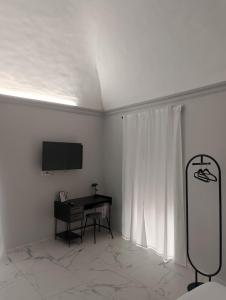 a white room with a desk and a tv on the wall at Vulcano Rooms 4 in Catania