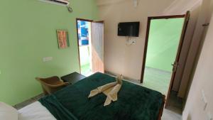 a bedroom with a green bed and a mirror at Ronazio Beach View Residency in Auroville
