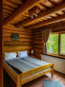 a bedroom with a bed in a log cabin at Craiasa Draganului in Poeni