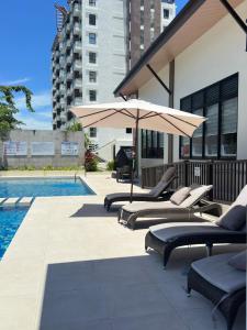 a group of lounge chairs and an umbrella next to a pool at Azure Edge in Dauis