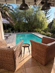 a swimming pool with two wicker chairs and a table at Almond Cottage Bed & Breakfast in Somerset West