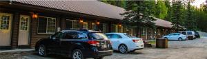 two cars parked in a parking lot in front of a building at Glacier Highland Motel in West Glacier