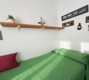a bedroom with a green bed and a shelf at La stanza di Giuly in Porto Santo Stefano