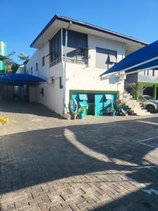 a white building with blue umbrellas in a parking lot at Tshedza Guest House in Pretoria