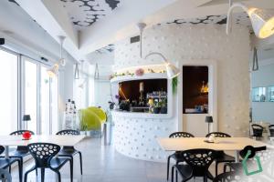 a restaurant with white walls and black chairs and tables at Hotiday Porto Cesareo Laguna in Porto Cesareo