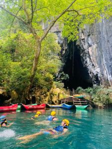 a group of people swimming in a river in front of a cave at Dolphin Home in Dong Hoi