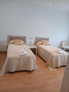 two beds in a room with wooden floors at Cecilia in Muros
