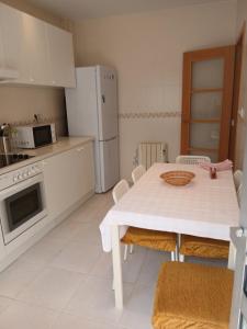 a kitchen with a white table and a white refrigerator at Cecilia in Muros +6 photos