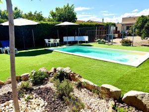 a backyard with a swimming pool and a yard with grass at Mas de la Maria in Cambrils