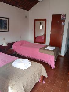 two beds in a room with pink sheets and a mirror at Hotel El Colonial in San Antonio Oeste