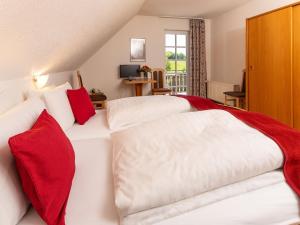 two beds in a hotel room with red and white pillows at Gut Ahe Landgasthof Cafe Event in Kirchhundem