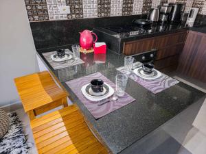 a kitchen counter with two plates and a pink tea pot at Apto Novo Duplex em Juqhey in Juquei