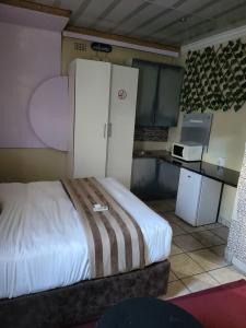 a room with a bed and a kitchen with a refrigerator at THK Properties in Pretoria