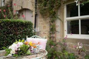 a wicker table with flowers on it in front of a house at Orchard Cottage in Ripon