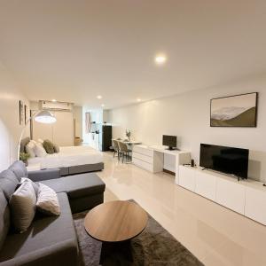 a living room with a couch and a tv at Elegant Modern White Suite in Chiang Mai
